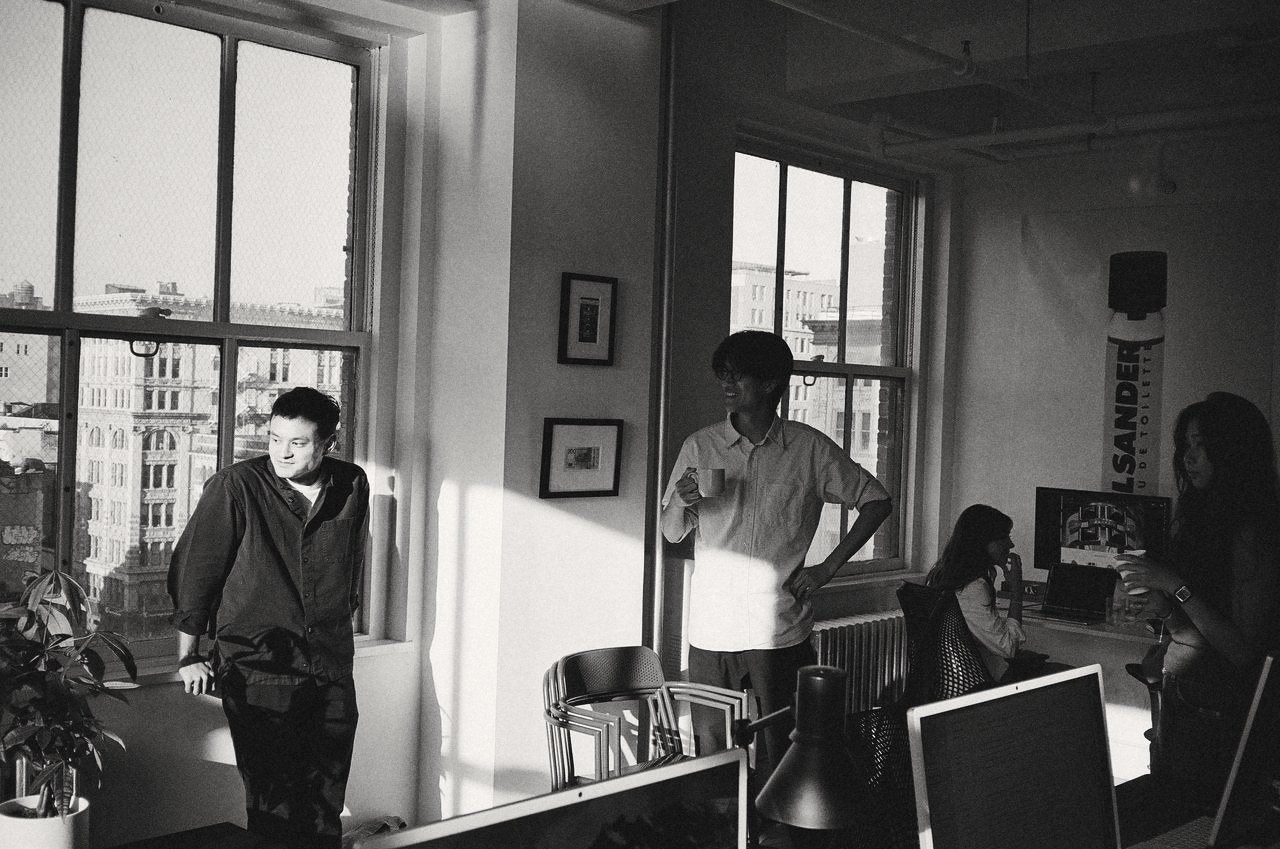 Two people talking by the studio windows in morning light